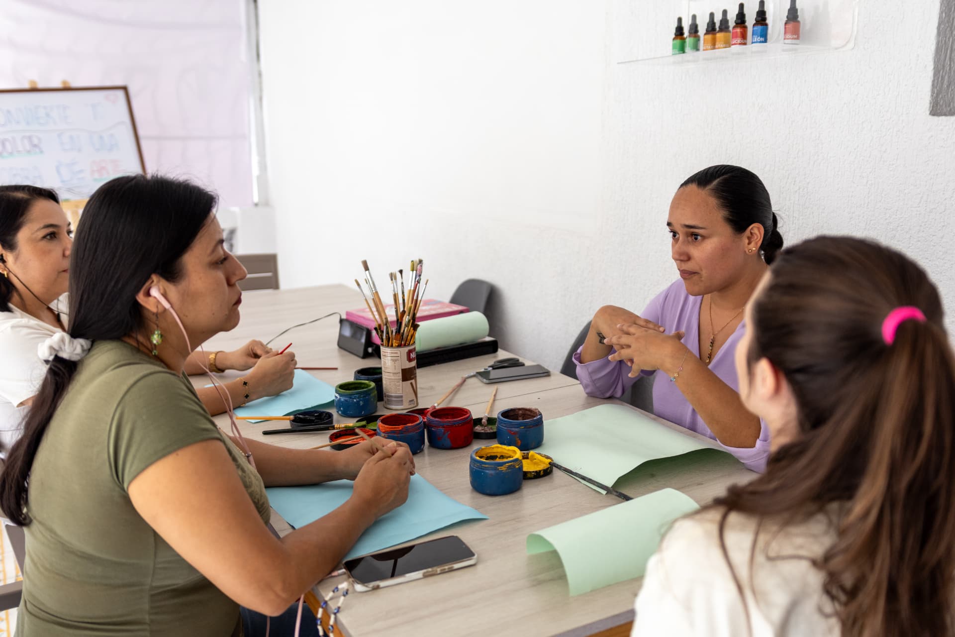 Encuentro de psicoartes en Géminis, con mujeres conversando y pintando alrededor de una mesa